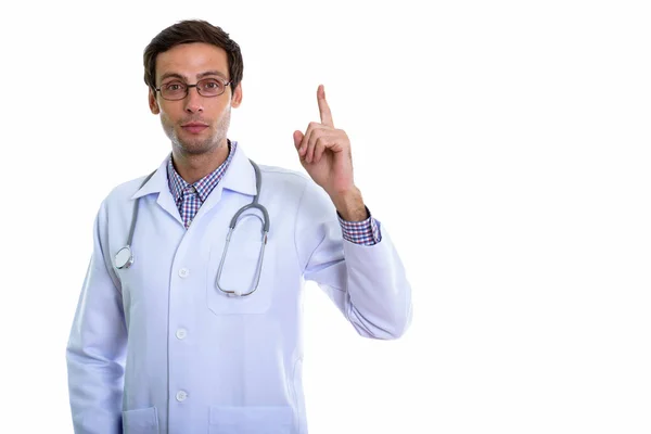 Studio shot of young handsome man doctor pointing finger up — Stock Photo, Image