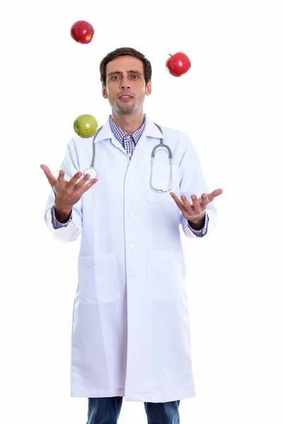 Студийный снимок молодого красивого врача, стоящего во время жонглирования — стоковое фото