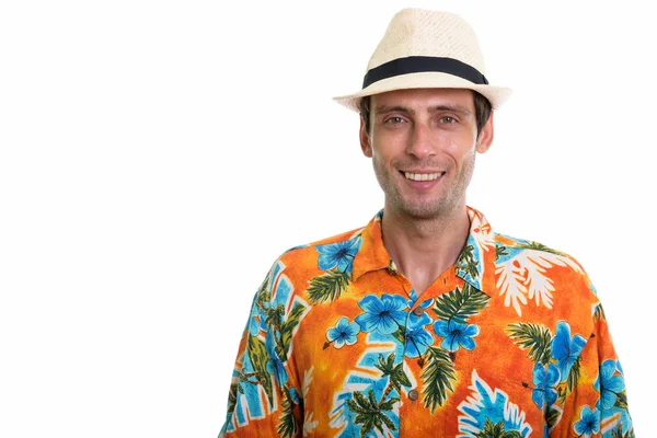 Studio shot of young happy tourist man smiling while wearing hat — Stock Photo, Image