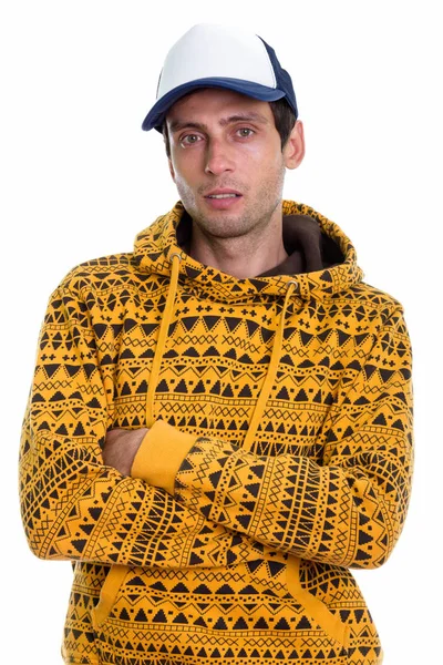 Studio shot of young handsome man wearing cap with arms crossed — Stock Photo, Image