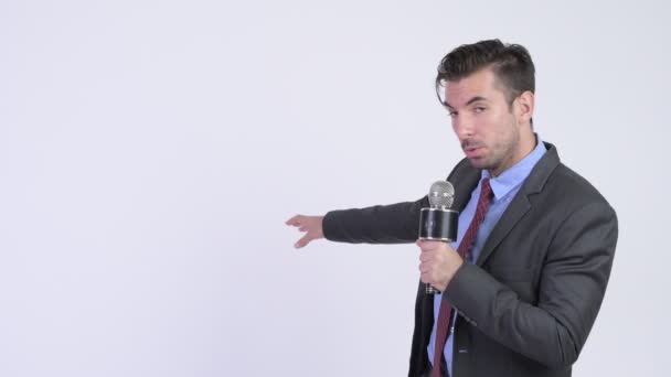 Joven empresario hispano guapo usando micrófono como presentador de noticias — Vídeo de stock