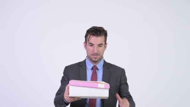 Νέος όμορφος Ισπανόφωνος επιχειρηματίας ανοίγοντας κουτί δώρου και κοιτάζοντας έκπληκτοι — Αρχείο Βίντεο