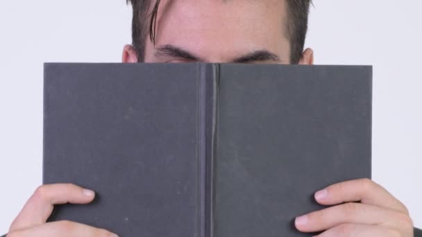 Jovem tímido empresário hispânico cobrindo rosto com livro — Vídeo de Stock