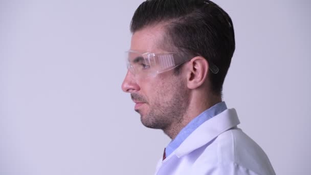 Visão de perfil de jovem feliz homem hispânico médico vestindo óculos de proteção — Vídeo de Stock