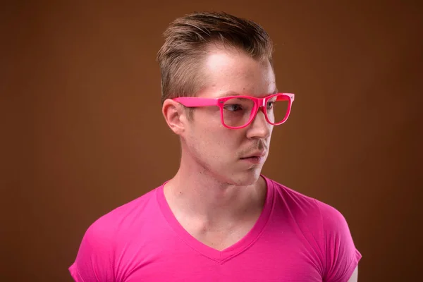 Jovem homem bonito vestindo camisa rosa e óculos contra bro — Fotografia de Stock