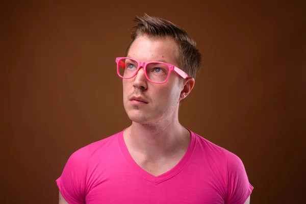 Joven hombre guapo con camisa rosa y anteojos contra bro — Foto de Stock