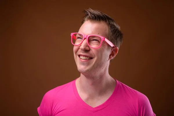 Joven hombre guapo con camisa rosa y anteojos contra bro — Foto de Stock