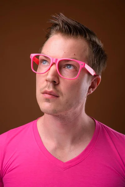 Mladý pohledný muž na sobě růžové košili a brýle proti bro — Stock fotografie