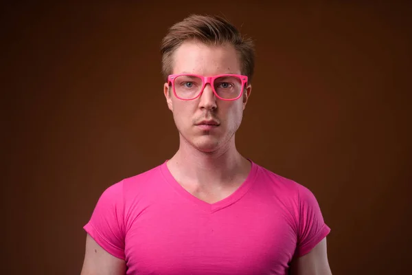 Jonge knappe man draagt roze shirt en brillen tegen bro — Stockfoto