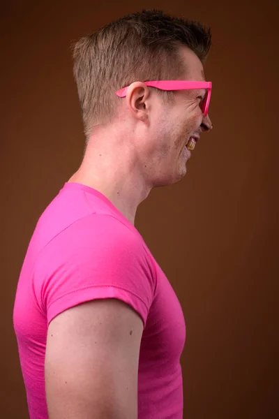 Joven hombre guapo con camisa rosa y anteojos contra bro — Foto de Stock