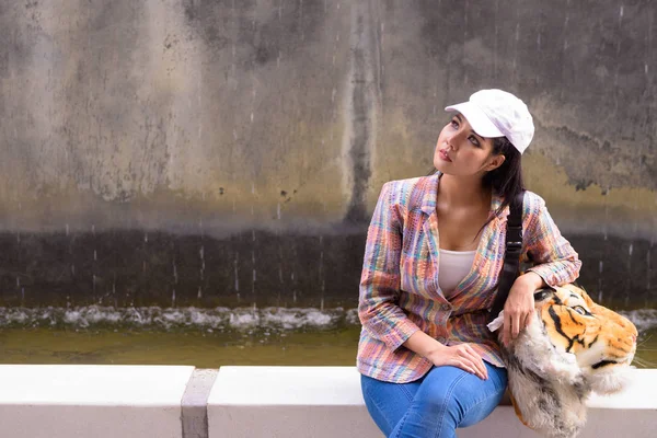 Retrato de joven hermosa mujer asiática sentada y pensando al aire libre —  Fotos de Stock