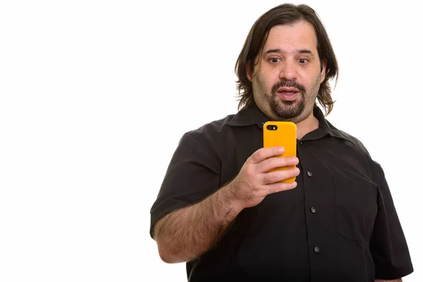 Fat Caucasian man using mobile phone looking shocked — Stock Photo, Image