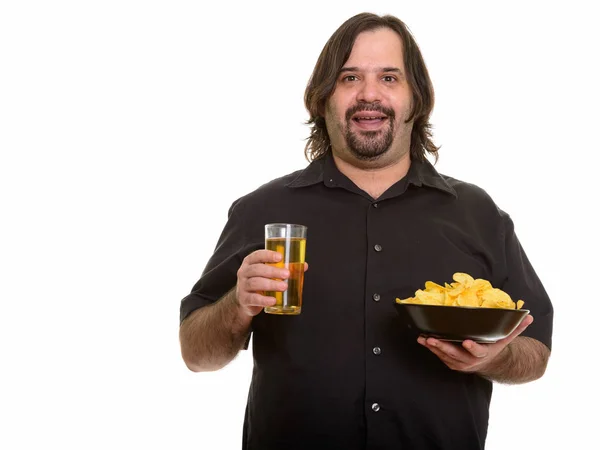 Glücklicher fetter kaukasischer Mann lächelt, während er eine Schüssel Chips in der Hand hält und — Stockfoto