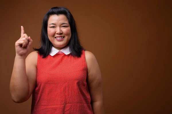Felice donna asiatica in sovrappeso che punta il dito verso l'alto mentre sorride — Foto Stock