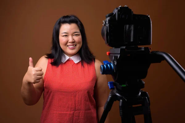 Sobrepeso asiático mujer vlogging en estudio con dslr cámara en trípode —  Fotos de Stock