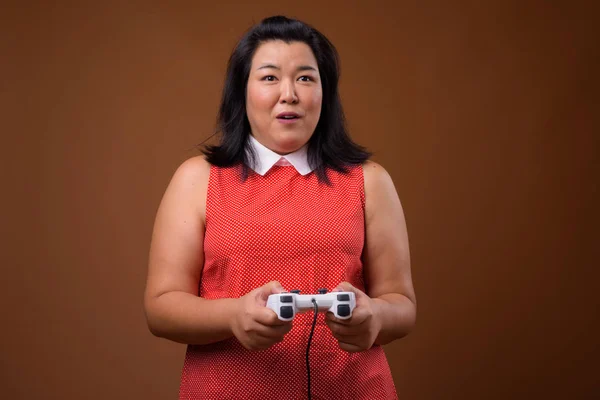Linda mulher asiática com sobrepeso jogando jogos de vídeo usando controlador de jogo — Fotografia de Stock