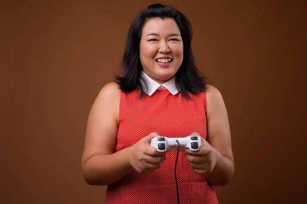 Hermosa mujer asiática con sobrepeso jugando videojuegos usando controlador de juego —  Fotos de Stock