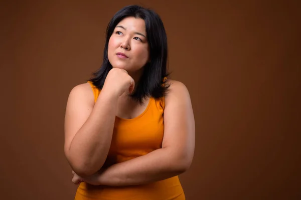 Linda mulher asiática com sobrepeso pensando e olhando para cima — Fotografia de Stock