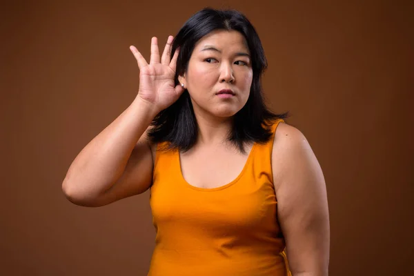 Retrato de hermosa mujer asiática con sobrepeso escuchando chismes —  Fotos de Stock