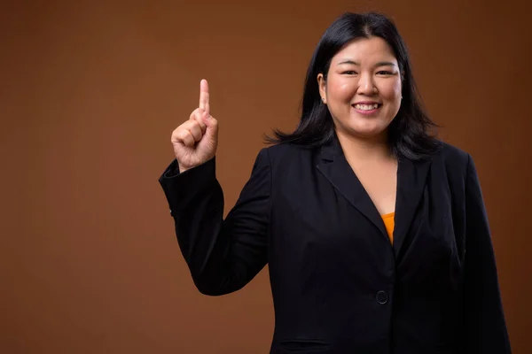 Feliz sobrepeso asiático empresaria apuntando dedo hacia arriba —  Fotos de Stock