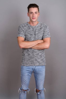 Gri arka planda gri gömlek giyen genç yakışıklı adam.
