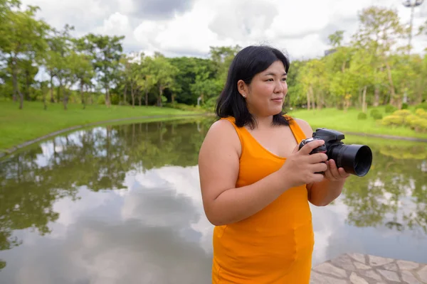 Vackra överviktiga asiatisk kvinna fotograf i park — Stockfoto
