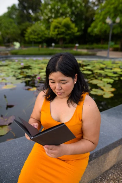 美丽的超重亚洲妇女阅读书在公园 — 图库照片