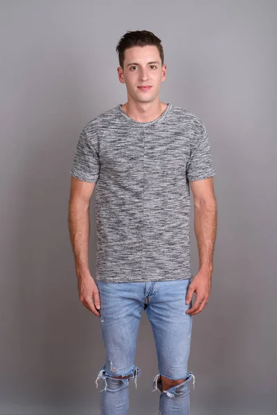 Young handsome man wearing gray shirt against gray background — Stock Photo, Image