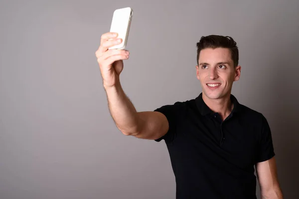 Jeune homme beau utilisant le téléphone mobile pour prendre selfie — Photo