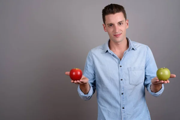 Jovem homem bonito segurando maçã vermelha e maçã verde — Fotografia de Stock