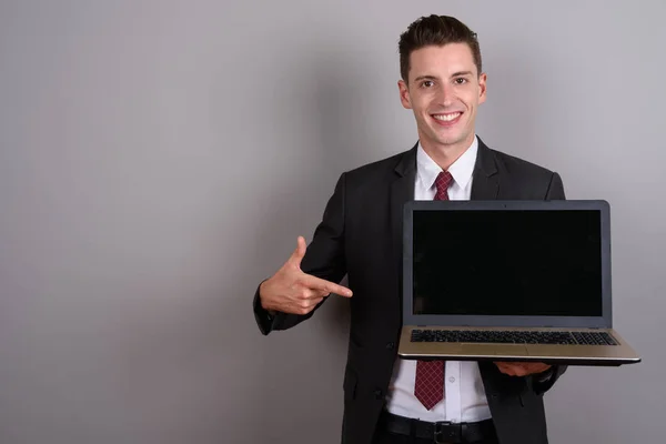 Jovem homem de negócios feliz segurando computador portátil com espaço de cópia — Fotografia de Stock