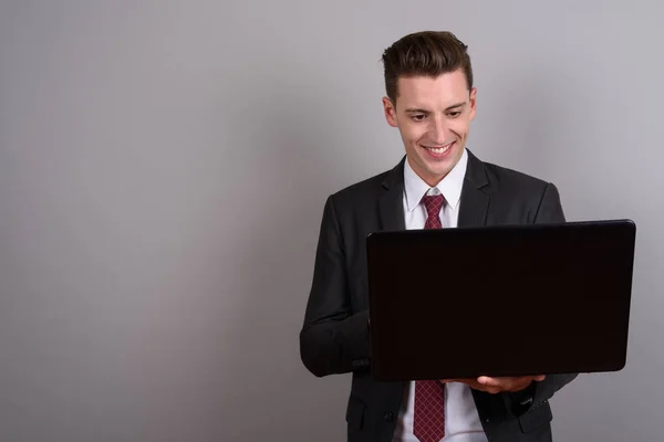 Empresário feliz sorrindo e usando computador portátil — Fotografia de Stock