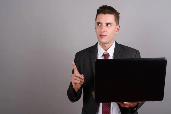 Young handsome businessman using laptop computer while thinking — Stock Photo, Image