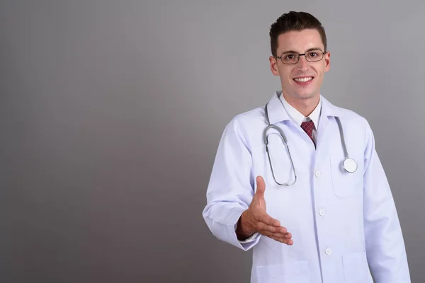 Joven hombre guapo médico sonriendo y dando apretón de manos —  Fotos de Stock