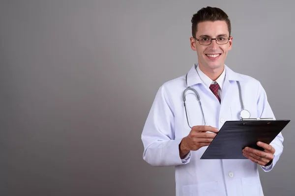 Ritratto di giovane bell'uomo medico che tiene appunti mentre sorride — Foto Stock