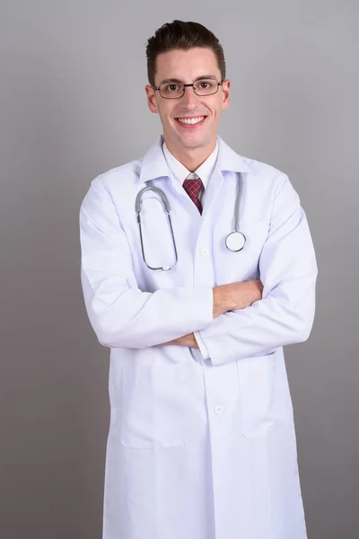 Jovem bonito homem médico sorrindo com os braços cruzados — Fotografia de Stock