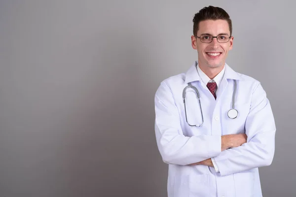 Fiatal jóképű férfi orvos mosolyogva karokkal keresztbe — Stock Fotó
