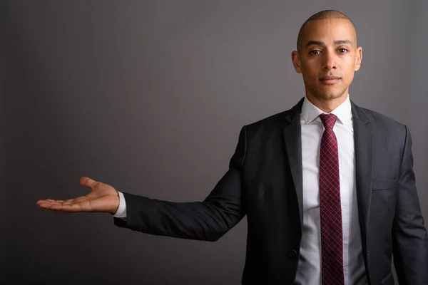 Handsome bald businessman showing copy space against gray background — Stock Photo, Image