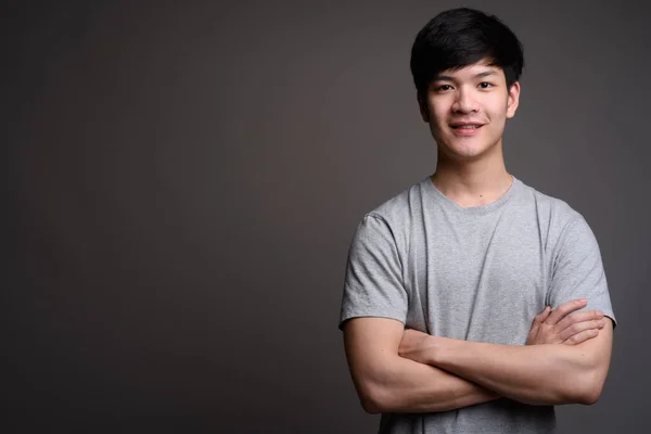 Junger hübscher asiatischer Mann lächelt mit verschränkten Armen — Stockfoto