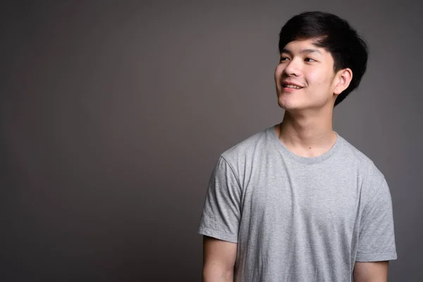 Gülümseyen ve düşünme genç yakışıklı Asyalı adam — Stok fotoğraf