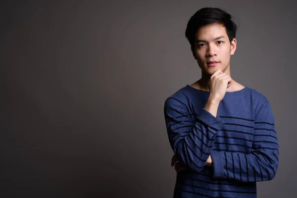 Young handsome Asian man with hand on chin — Stock Photo, Image