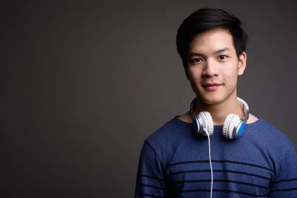 Kulaklıklar giyen genç yakışıklı Asya adam portresi — Stok fotoğraf
