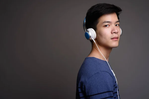 Молоді азіатські красенем слухати музику з навушниками — стокове фото