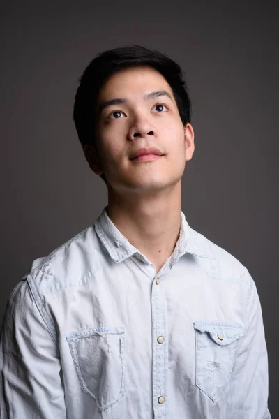 Studioporträt eines jungen hübschen asiatischen Geschäftsmannes, der nach oben schaut — Stockfoto