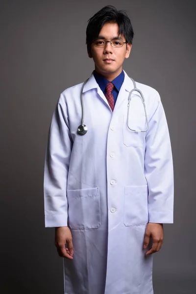 Retrato de un joven médico asiático sobre fondo gris —  Fotos de Stock