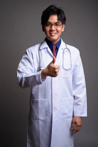 Junge hübsche asiatische Mann Arzt lächelt und gibt Daumen nach oben — Stockfoto
