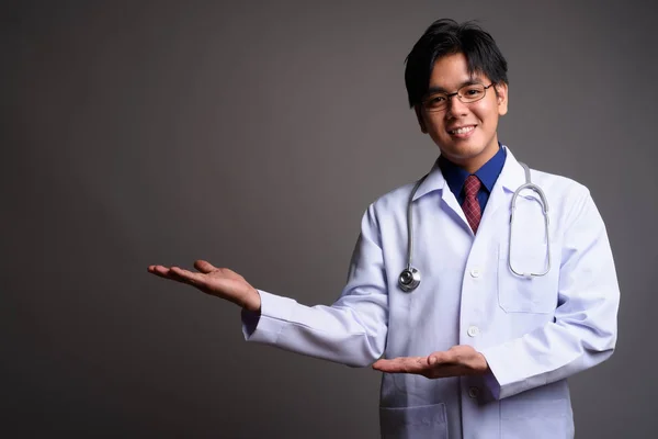 Χαρούμενος νεαρός ασιατικές γιατρός, χαμογελώντας και δείχνοντας αντίγραφο χώρου — Φωτογραφία Αρχείου