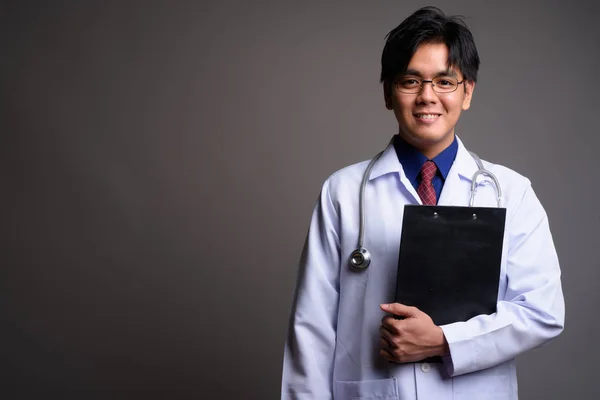 Πορτρέτο της Ασίας νεαρός γιατρός χαμογελώντας με πρόχειρο — Φωτογραφία Αρχείου