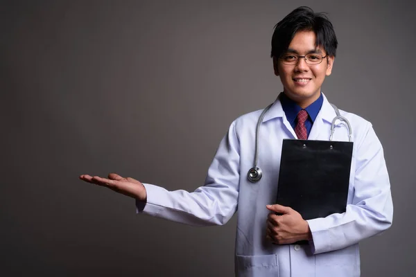 Portret młodego szczęśliwym człowiekiem Asian lekarza pokazuje miejsce — Zdjęcie stockowe