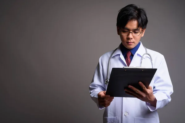 亚洲青年医生从剪贴板阅读清单的肖像 — 图库照片